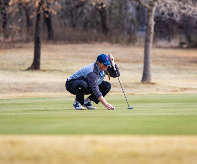 UCO golfer lines up the ball on the green for the putt. (Drew Rayburn/The Vista)