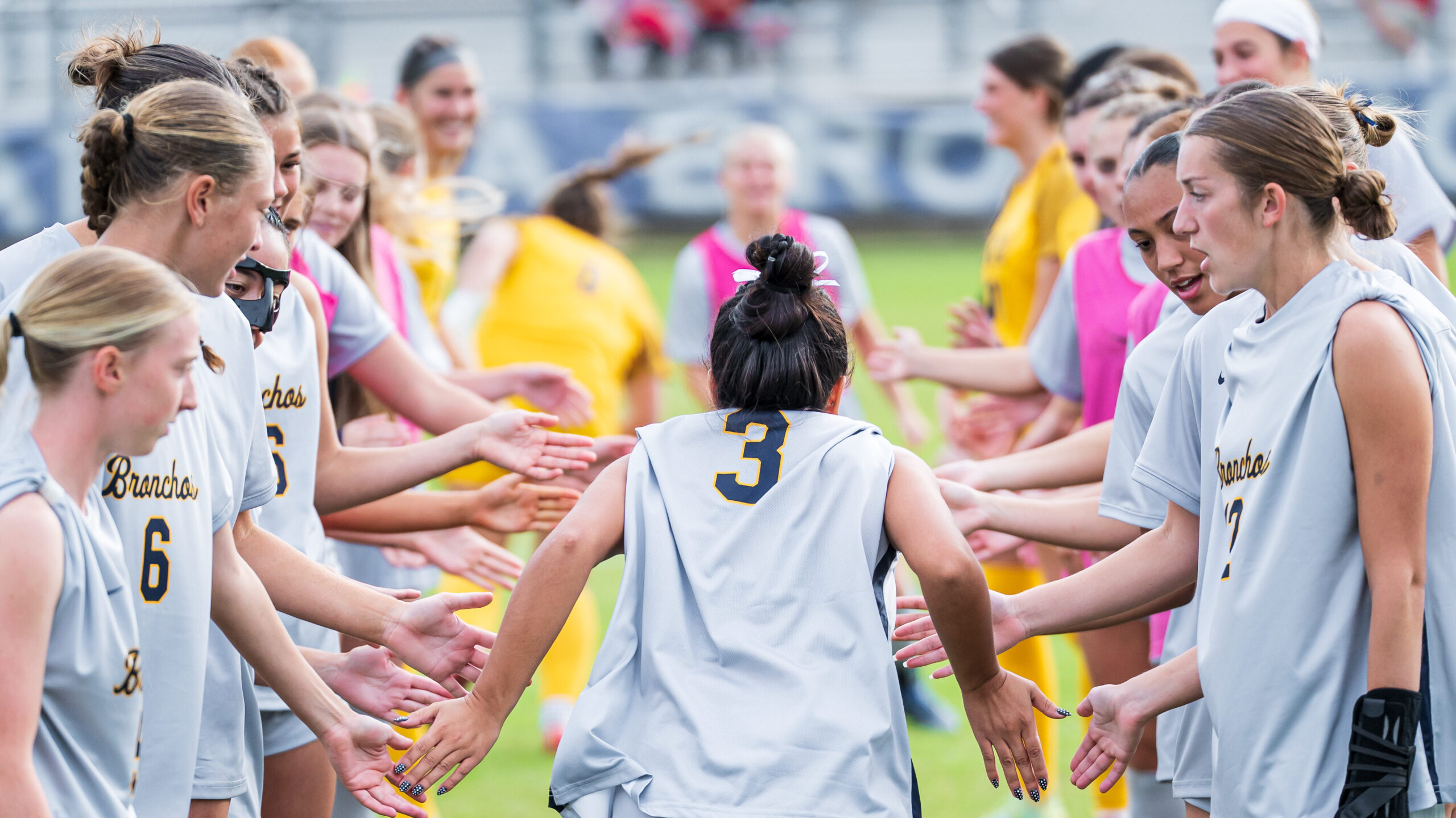 UCO Women's Soccer team lines up and passing high-fives with a player wearing jersey number 3.