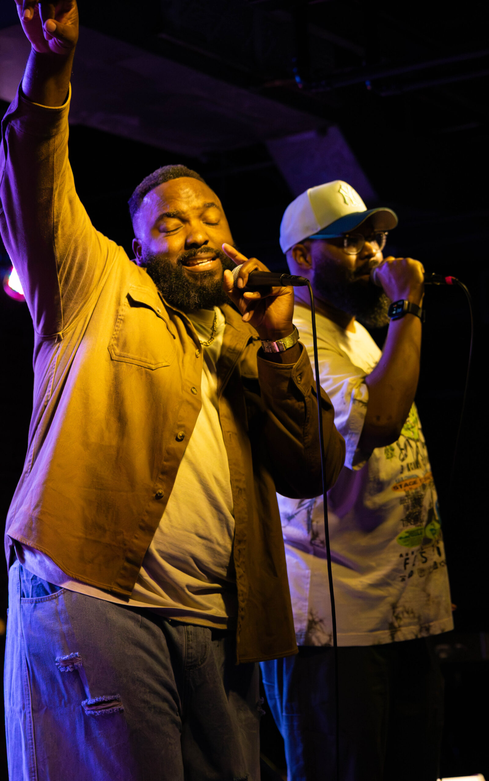 Tony Foster Jr. and Sid Carter sing together with arms in the air. (Maycee Elerick/The Vista)