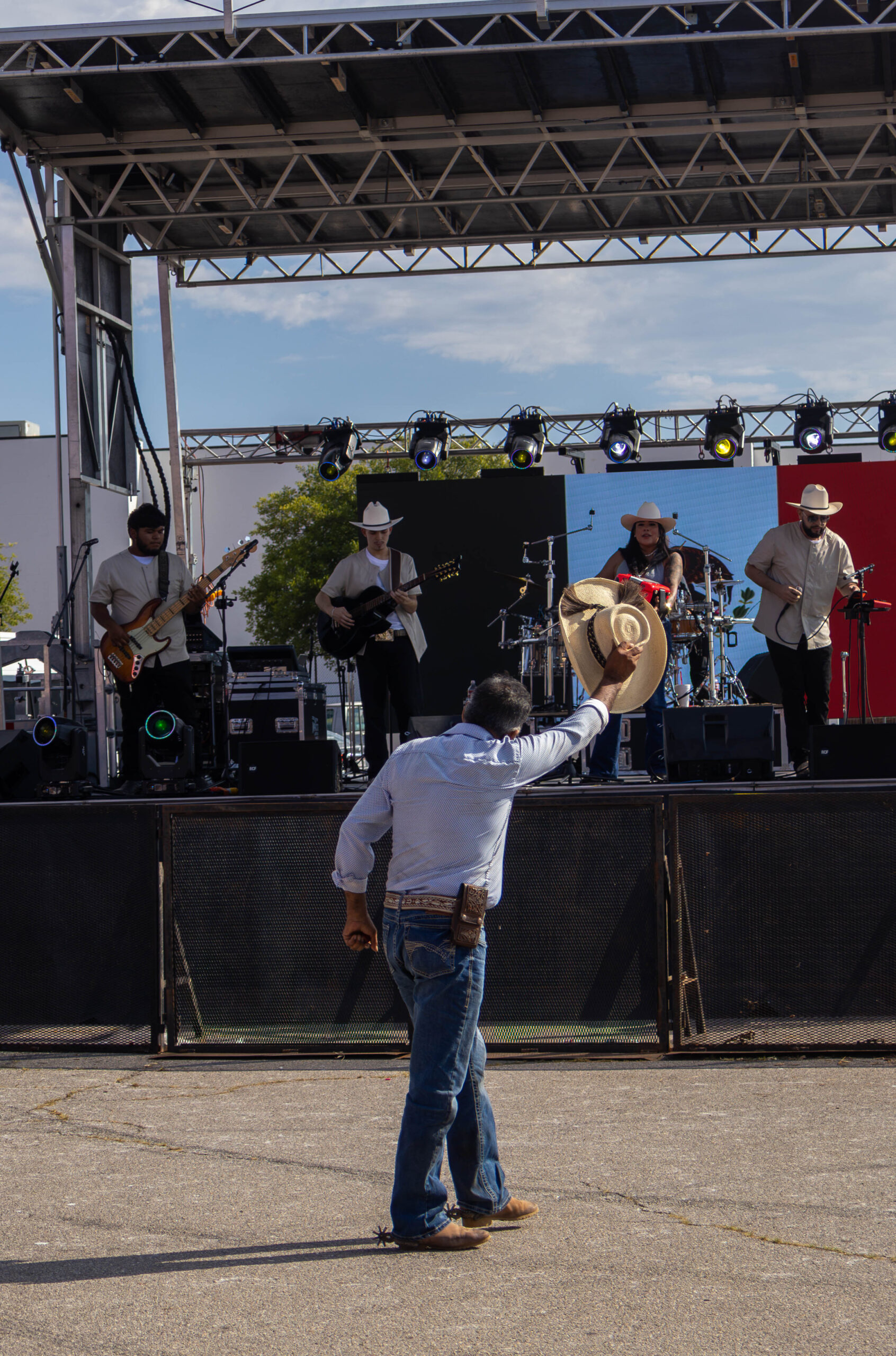 Man lifts his hat towards stage after dancing. (Maycee Elerick/The Vista)