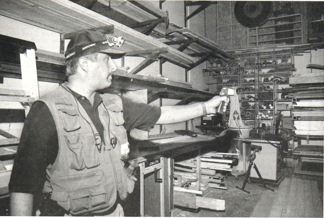 A ghost hunter is depicted in a black and white photo holding up a thermal gun inside UCO's Mitchell Hall Theater.